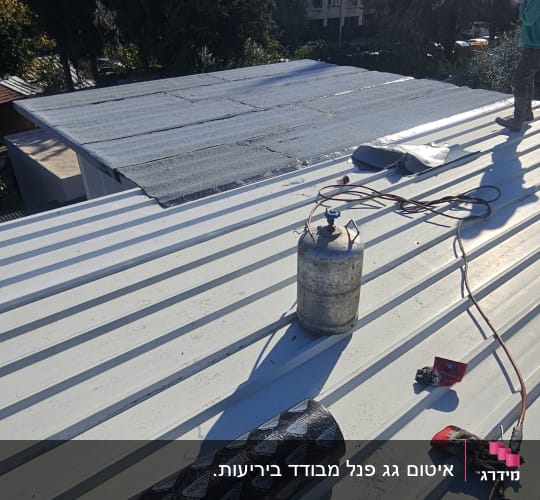 עבודת איטום על גג עם יריעות וכלים מתאימים